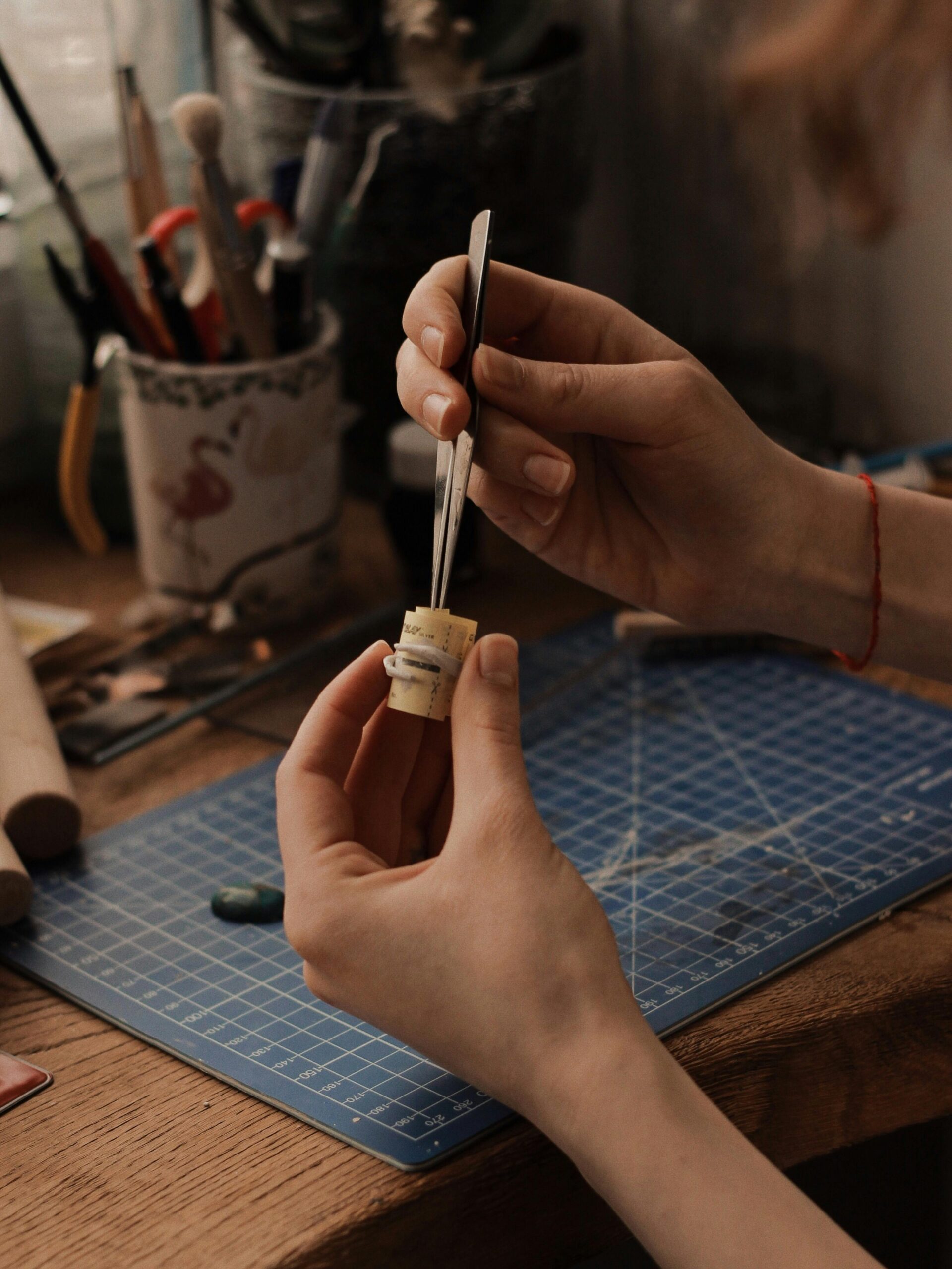 Close-up of hands crafting jewelry with tools in a workshop.