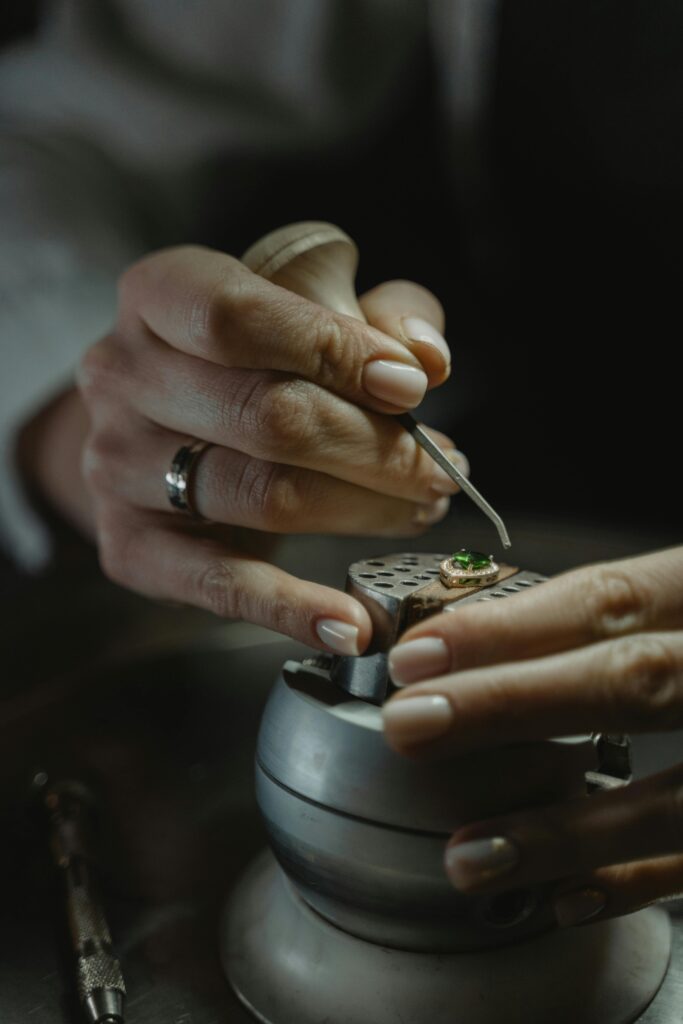 Close-up of a jeweler skillfully crafting an emerald ring, showcasing precision and detail.